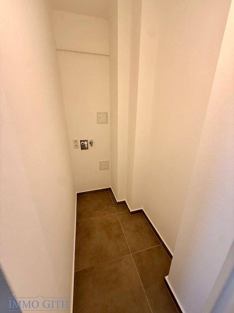 Praktischer Hauswirtschaftsraum mit Anschlüssen für Waschmaschine und Trockner, gefliestem Boden.