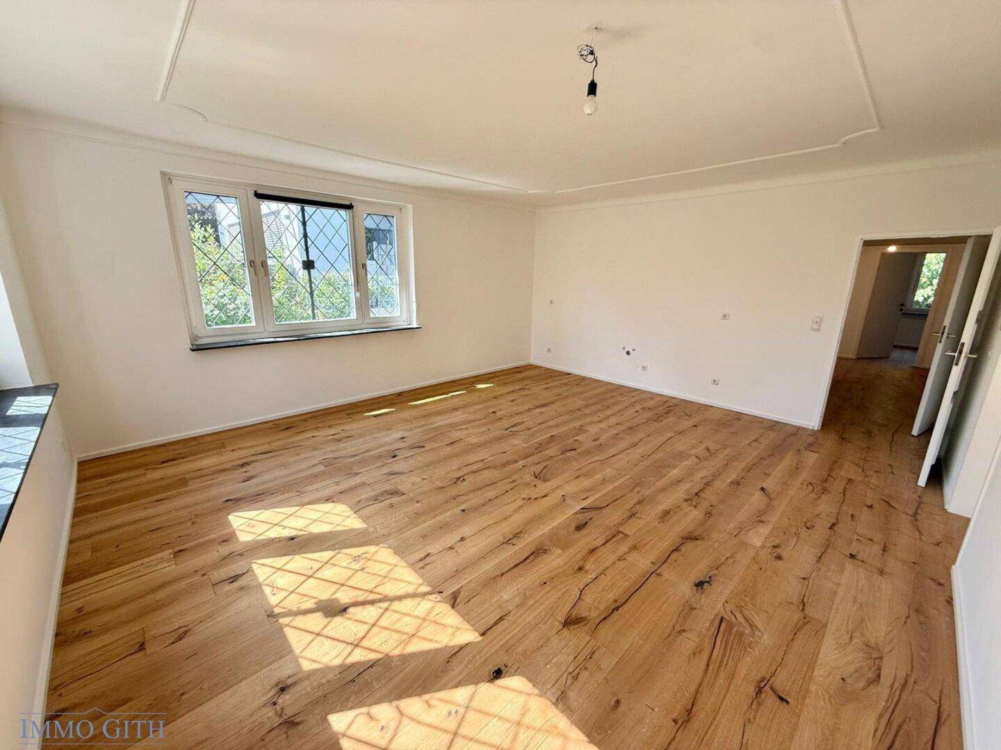 Lichtdurchfluteter Raum mit Holzboden und dekorativer Deckenleiste, bietet viel Platz zum Gestalten.