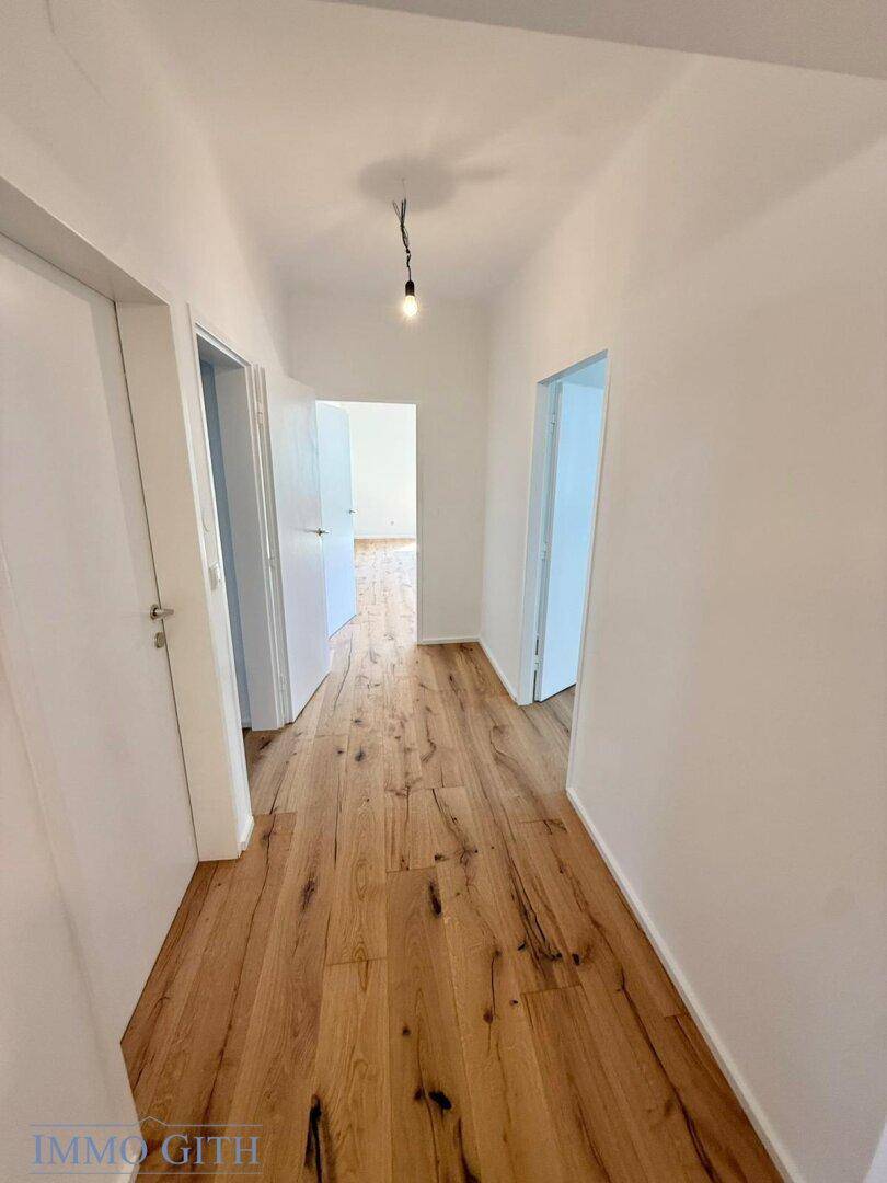 Heller Flur mit Holzboden, der zu verschiedenen Räumen führt und eine offene Atmosphäre schafft.