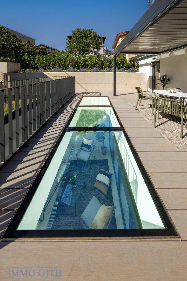 Glasboden auf der Terrasse bietet Einblick in den darunterliegenden, hellen Wohnraum.