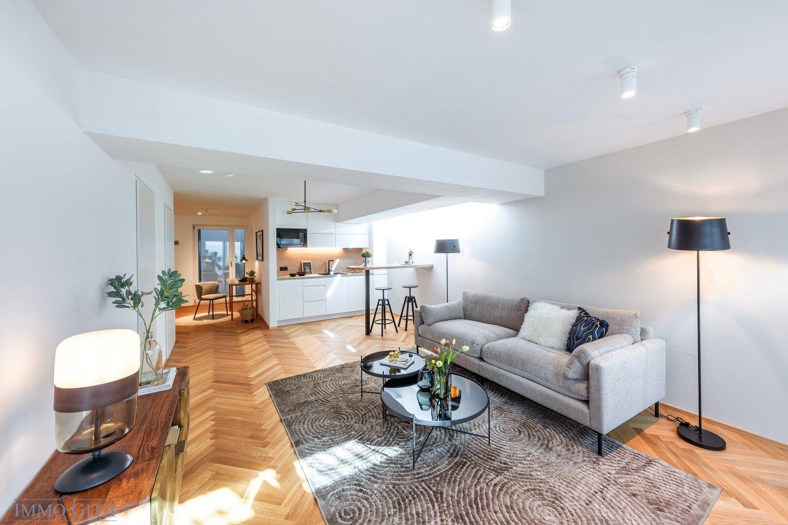 Moderner Wohnbereich mit Sofa, Couchtisch und integrierter Küchenzeile, ideal für Gäste.