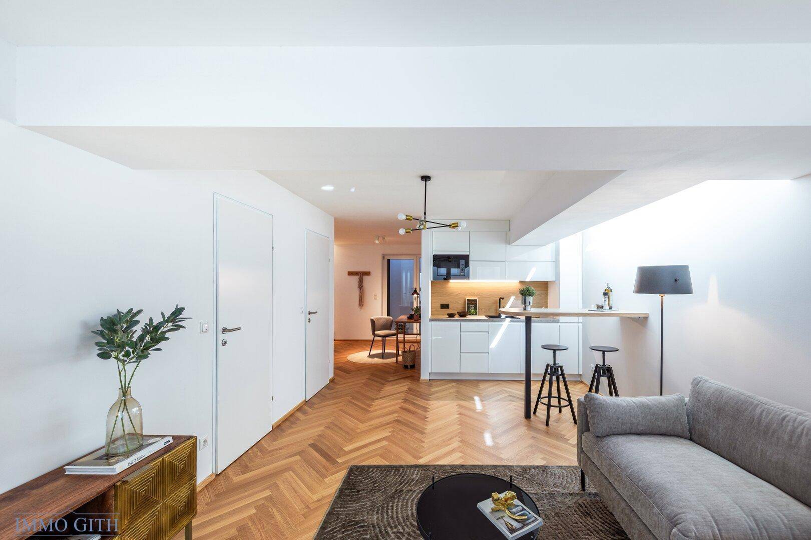 Wohnzimmer mit integrierter Küchenzeile und Blick auf den Flur mit modernen weißen Türen.