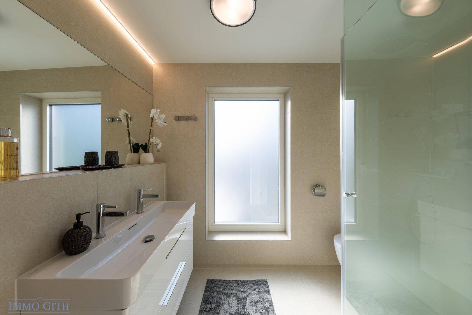 Modernes Badezimmer mit Doppelwaschbecken, großem Spiegel und begehbarer Dusche mit Glaswand.