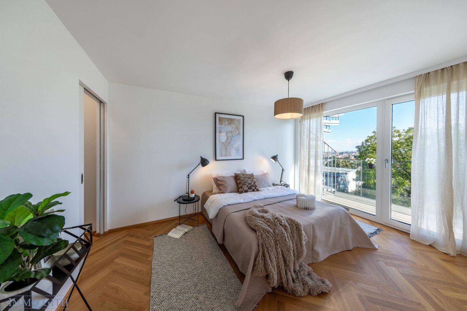 Gemütliches Schlafzimmer mit Doppelbett, Fischgrätparkett und großen Fenstern, die viel Licht hereinlassen.