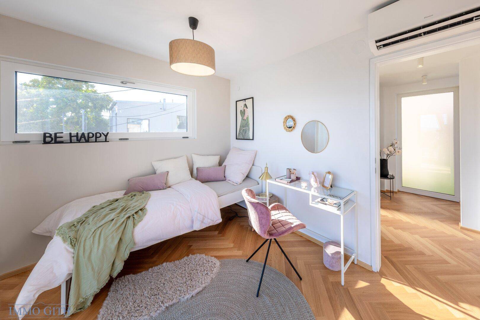 Helles Schlafzimmer mit Tagesbett, Schreibtisch und Klimaanlage, ideal für Gäste oder Kinder.