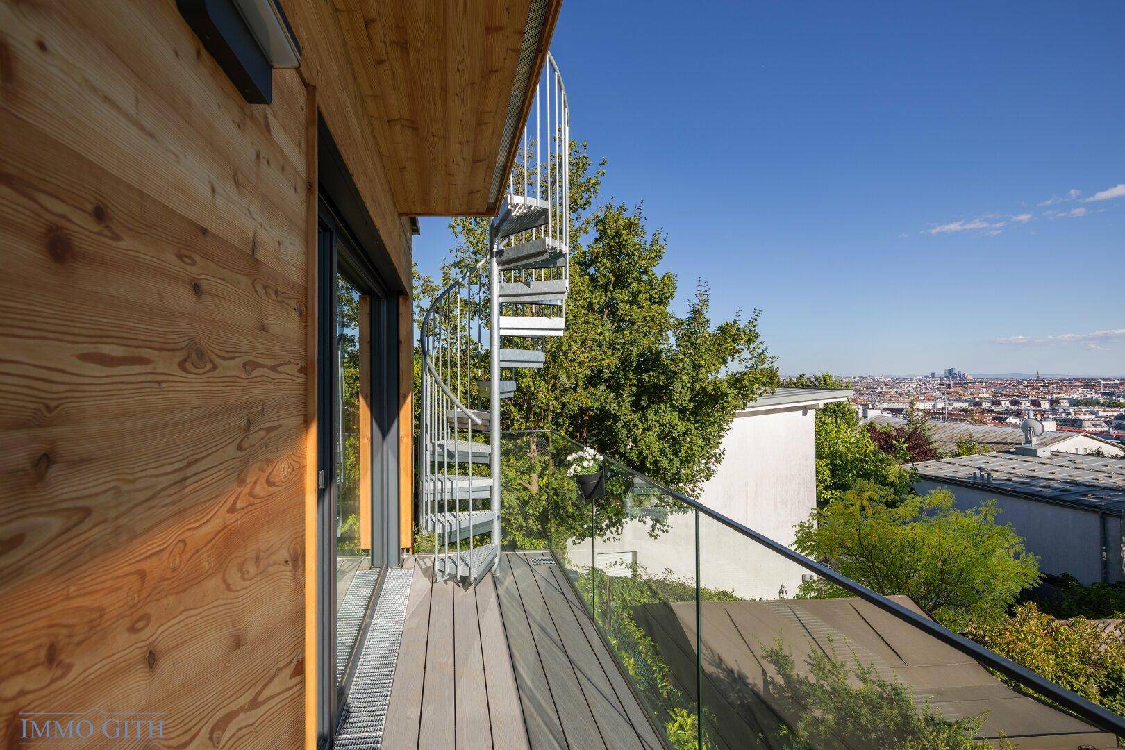 Balkon mit eleganter Wendeltreppe, die zu einer weiteren Ebene führt, und weitem Stadtblick.
