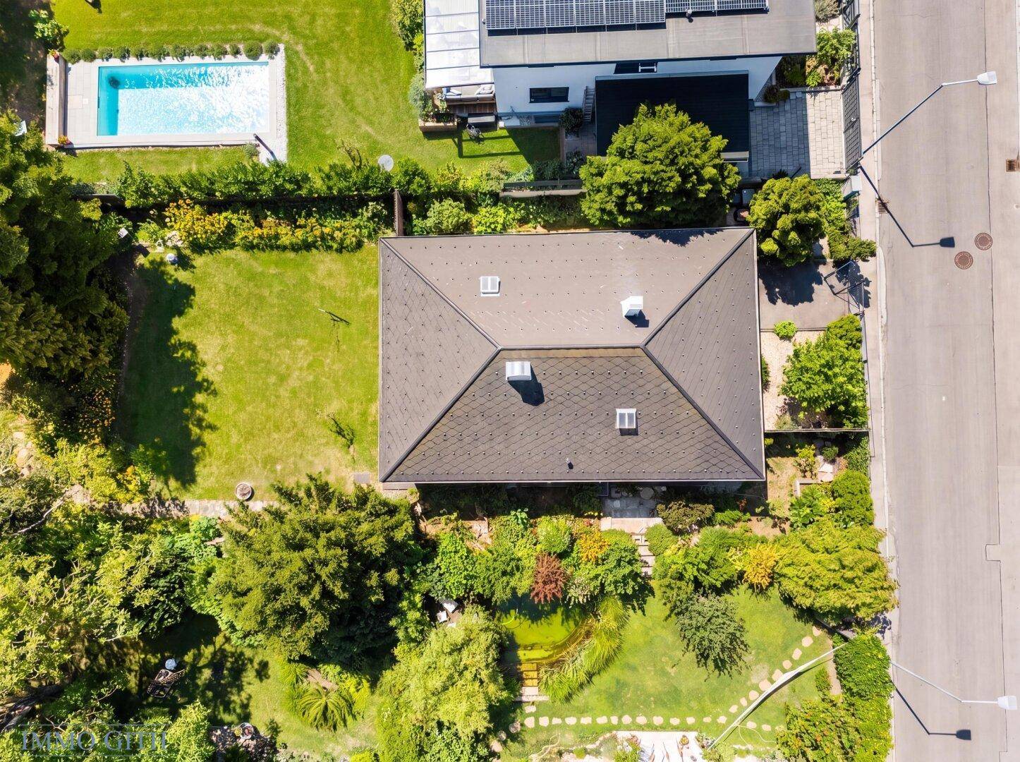 Luftaufnahme des Hauses mit großem Garten und angrenzendem Poolbereich des Nachbarn.