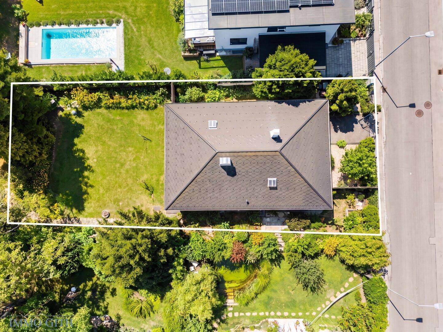 Luftaufnahme des Hauses mit großem Garten und angrenzendem Poolbereich des Nachbarn.