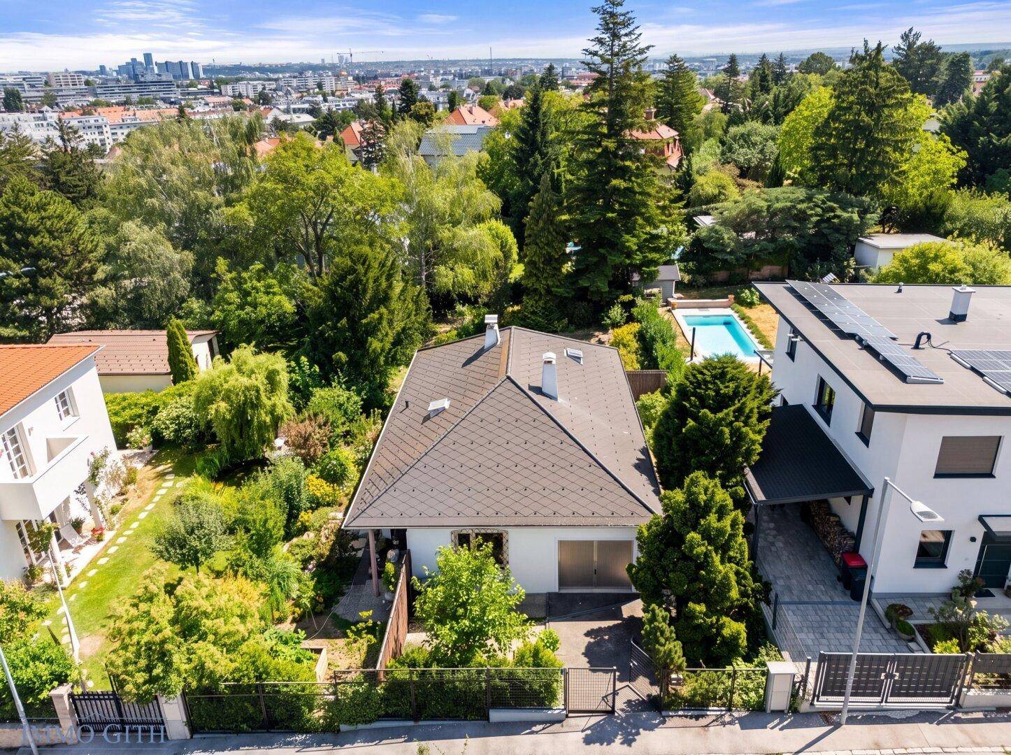 Freistehendes Haus mit Garten, umgeben von Grünflächen und Blick auf die Stadt in der Ferne.