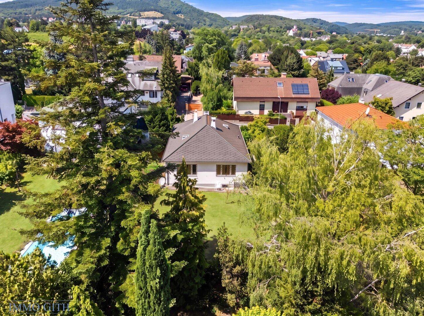 Haus eingebettet in üppiges Grün mit weitem Blick auf die umliegende Landschaft und Berge.