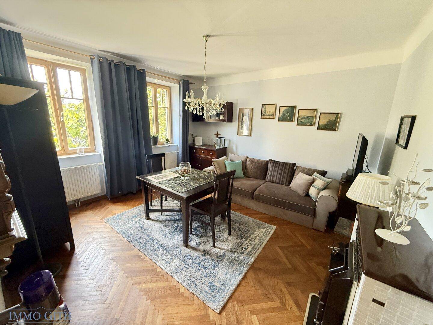 Gemütliches Wohnzimmer mit Fischgrätparkett, Esstisch und bequemer Couch.