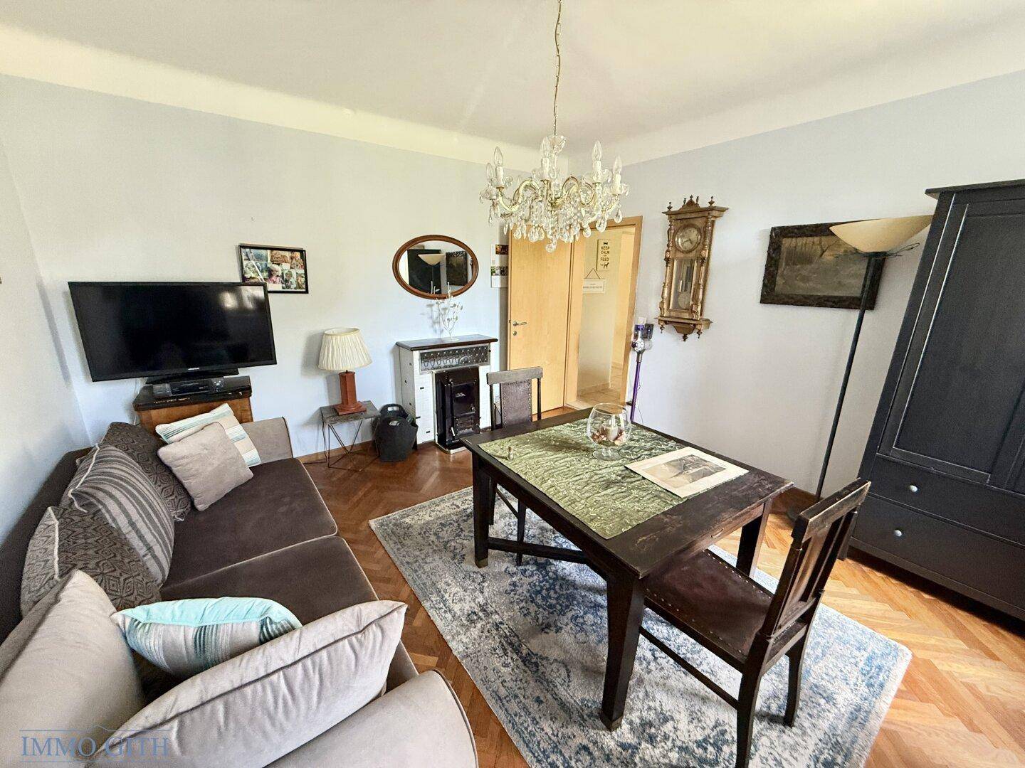 Wohnzimmer mit klassischem Parkettboden, Sofa, Esstisch und traditionellen Dekorationen.