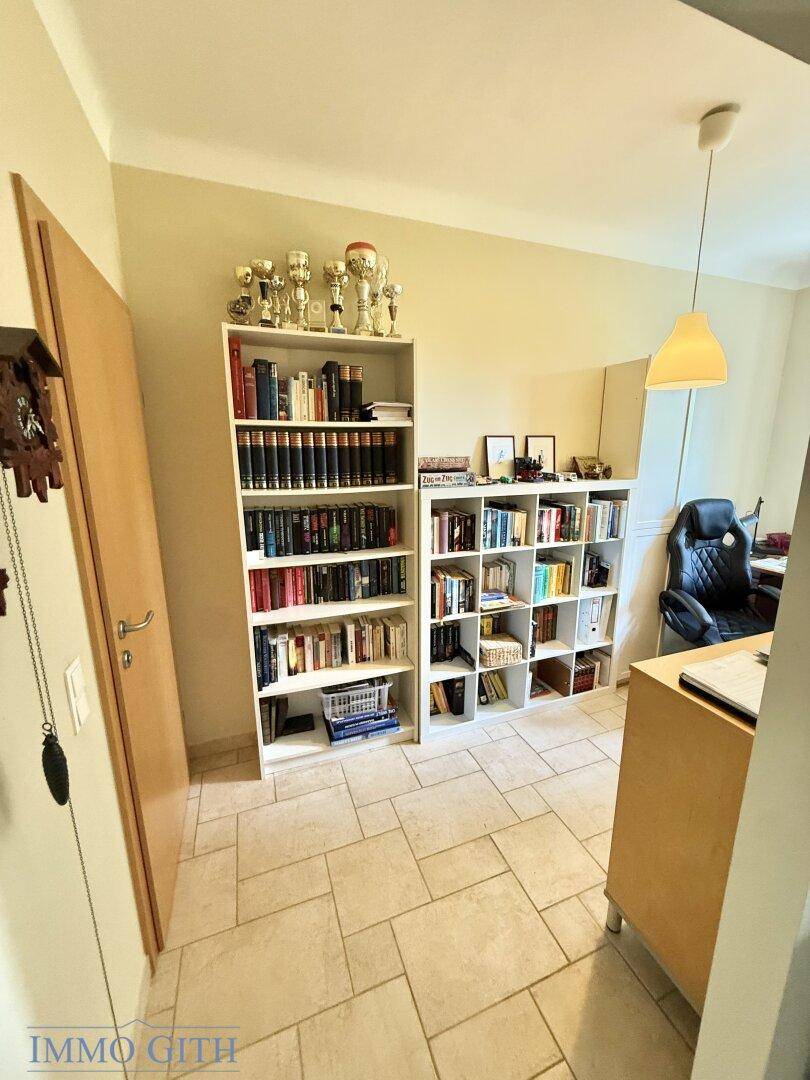 Helles Arbeitszimmer mit Fliesenboden und Bücherregalen.