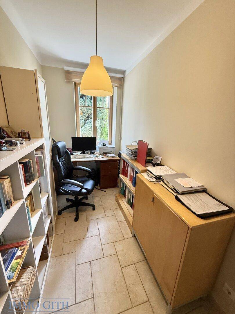 Arbeitszimmer mit Schreibtisch, Bürostuhl und Blick ins Grüne durch das Fenster.