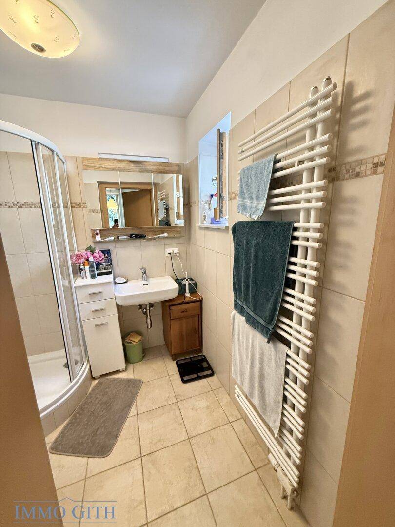 Badezimmer mit Dusche, Waschbecken, WC und beheiztem Handtuchhalter.