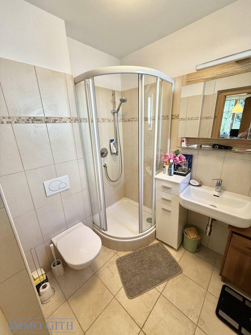 Modernes Badezimmer mit Eckdusche, WC und Fliesen in hellen Farbtönen.