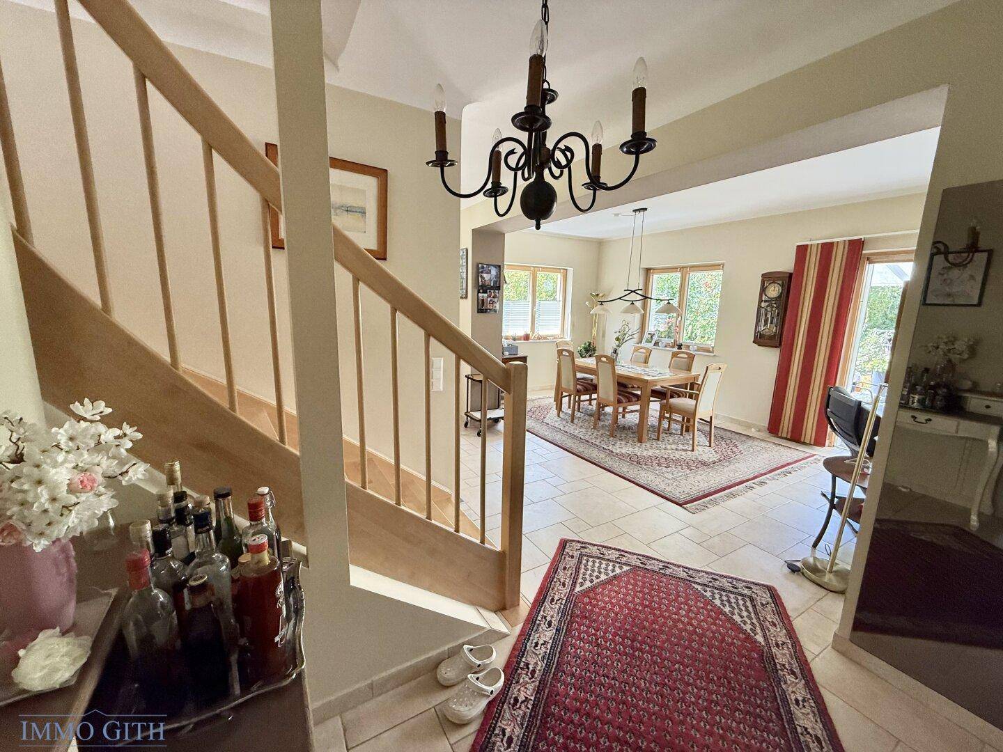 Geräumiger Essbereich mit Holztisch, Stühlen und Zugang zur Treppe.