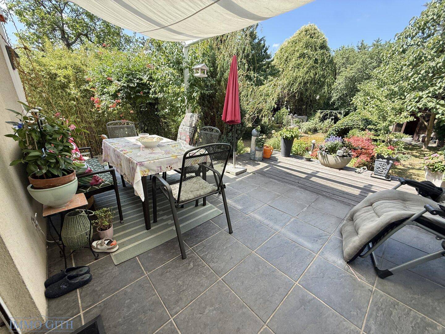 Gemütliche Terrasse mit Esstisch, Stühlen und Blick auf den grünen Garten.