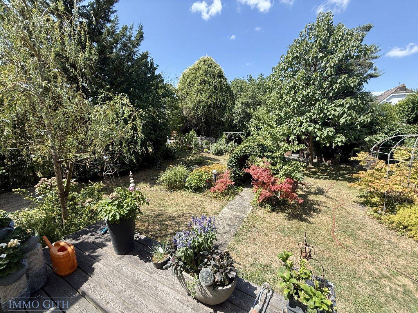 Gepflegter Garten mit Rasenfläche, verschiedenen Pflanzen und Bäumen.
