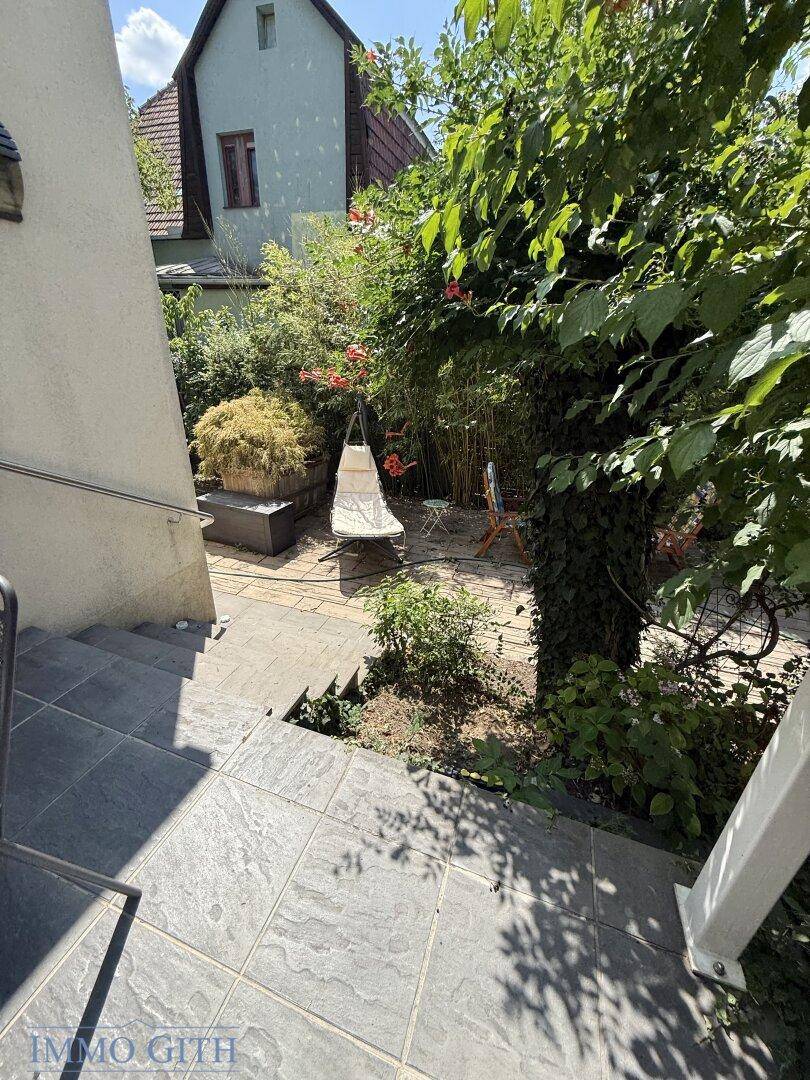 Außentreppe führt hinunter zu einem kleinen Gartenbereich mit Sitzgelegenheit.