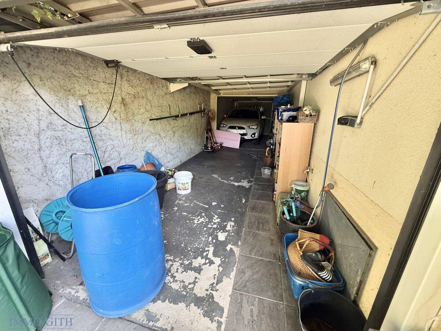 Geräumige Garage mit Stauraum und einem geparkten Auto im hinteren Bereich.