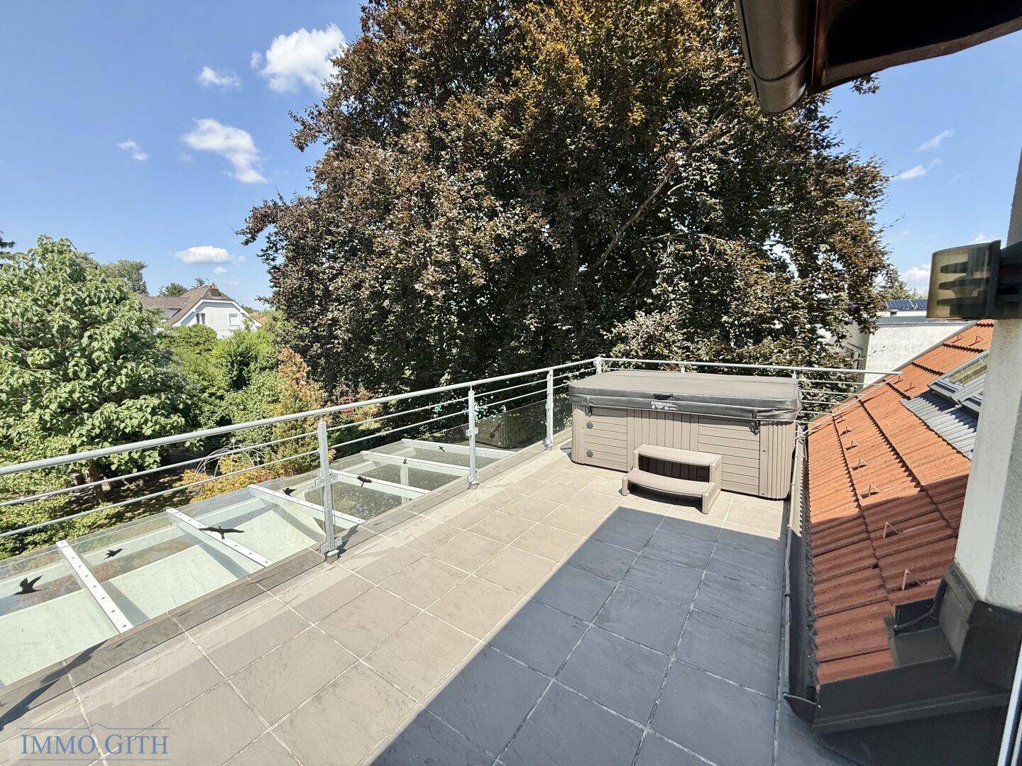 Dachterrasse mit Whirlpool und weitem Blick auf die umliegenden Bäume und den Garten.
