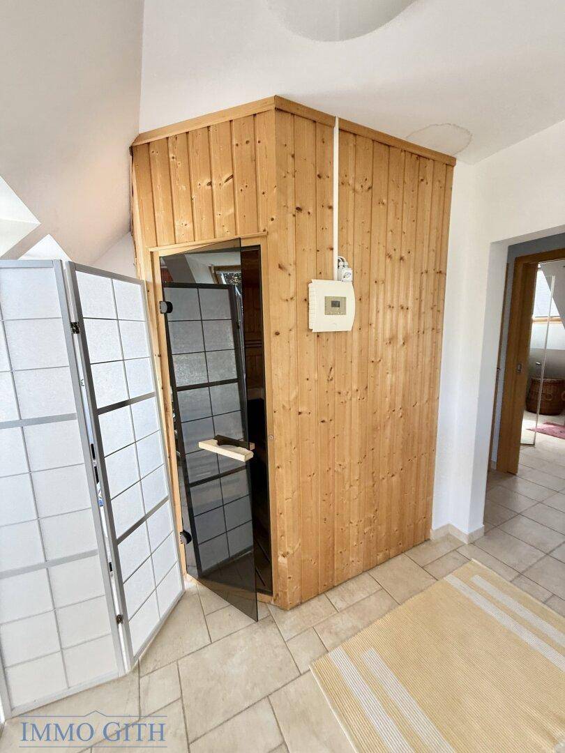 Holzvertäfelte Sauna-Kabine in einem Raum mit hellen Fliesen, bereit zur Nutzung.