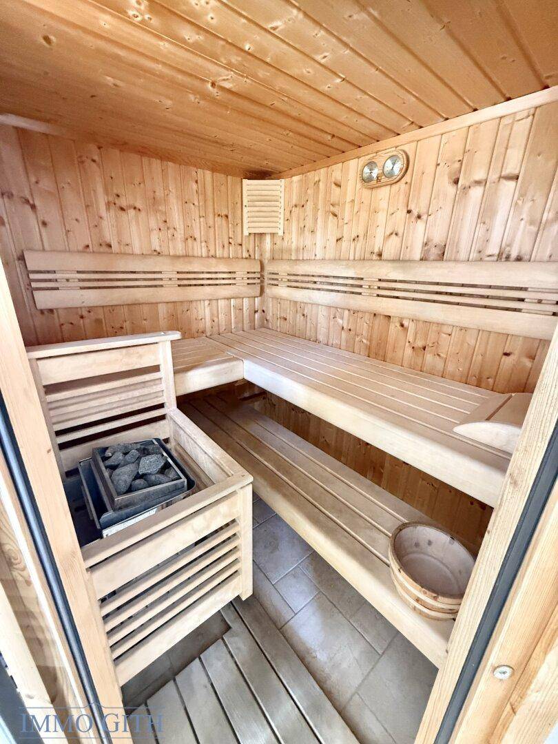 Innenansicht der Holzsauna mit mehreren Bänken und einem Saunaofen.