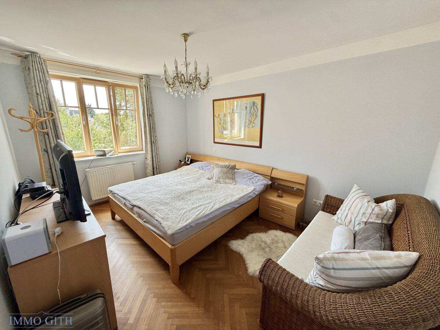 Gemütliches Schlafzimmer mit Doppelbett, Holzmöbeln und Fischgrätparkettboden.