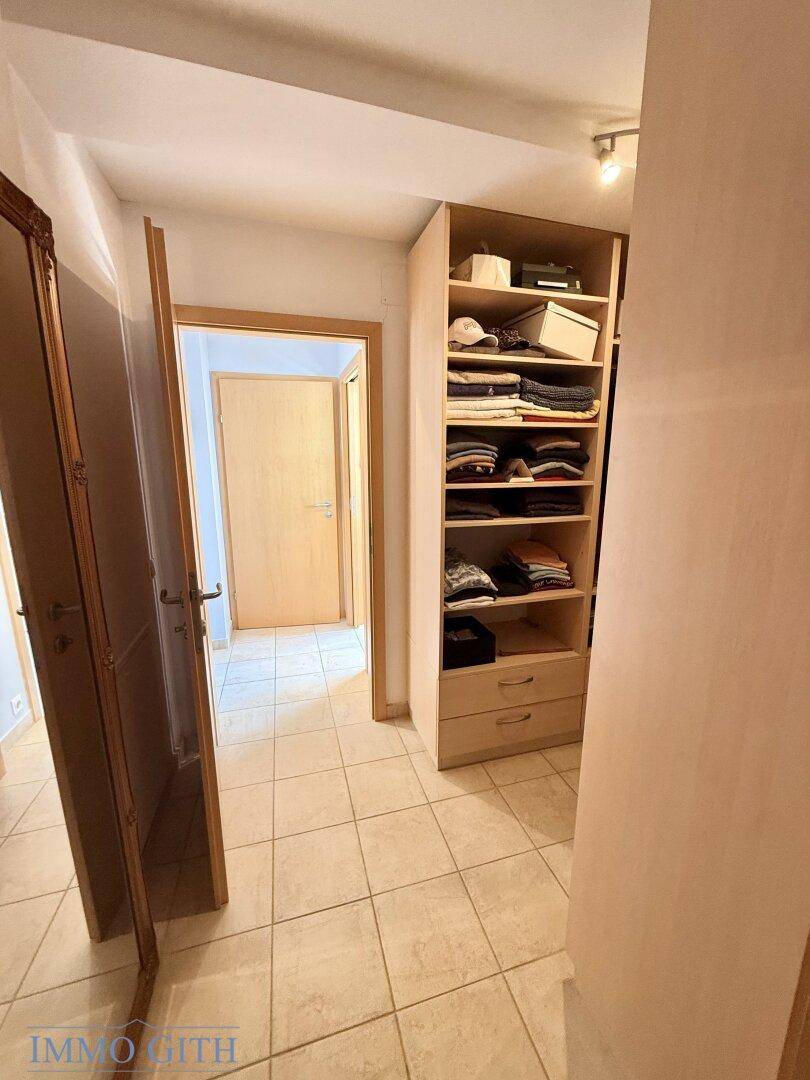 Heller Flur mit Fliesenboden und praktischem Einbauschrank, der zu weiteren Räumen führt.