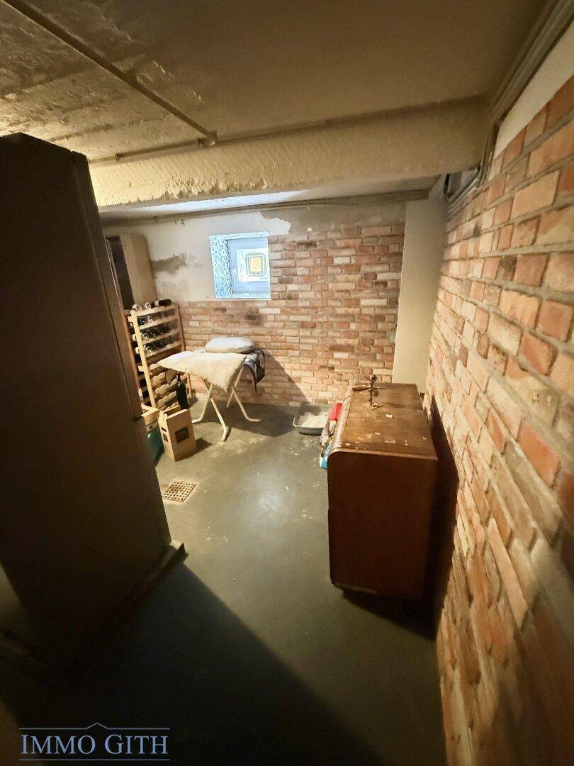 Kellerraum mit unverputzten Ziegelwänden, Betonboden und einem kleinen Fenster, ideal als Lagerraum.