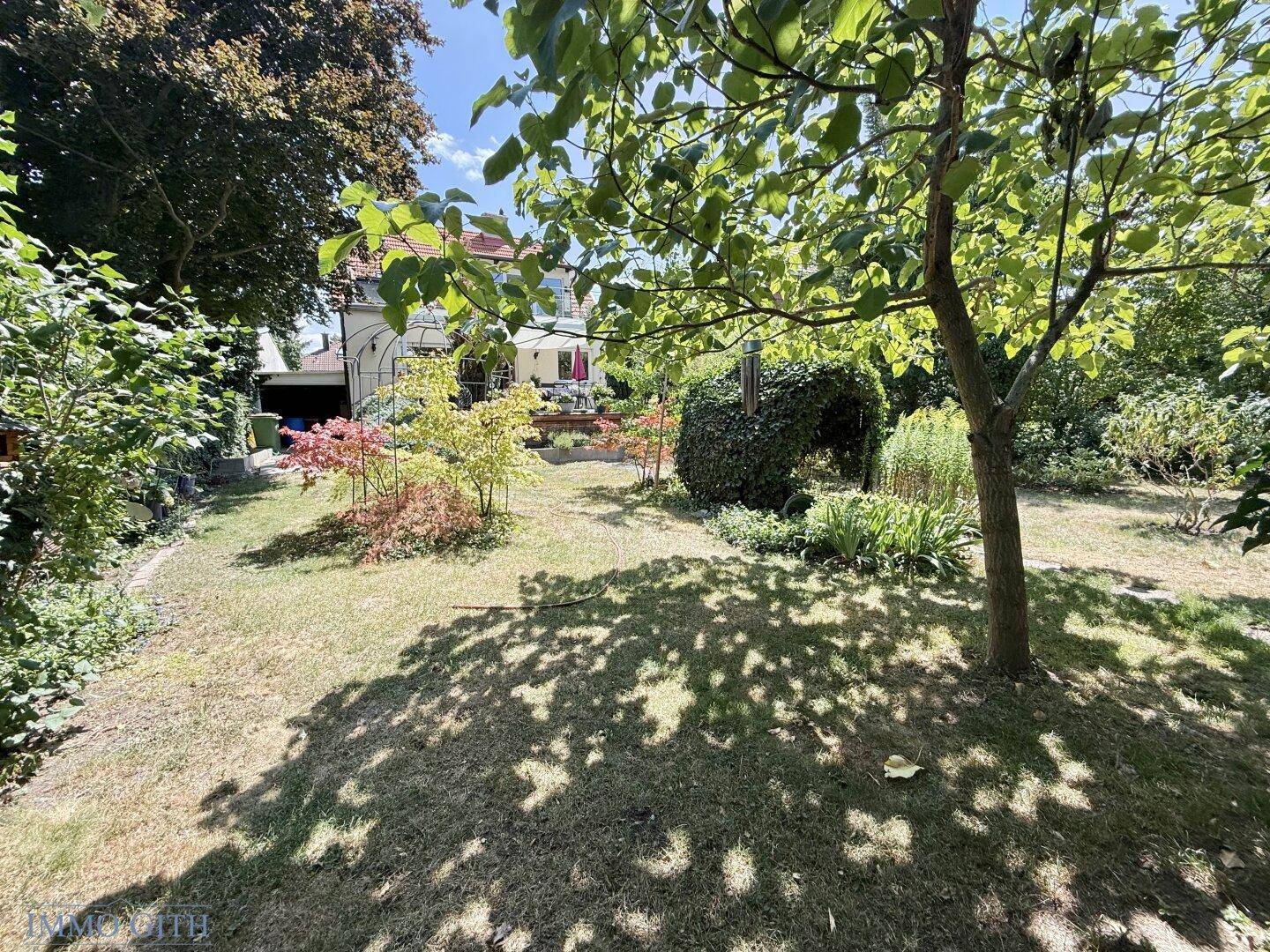 Weitläufiger Garten mit großer Rasenfläche und Blick auf das Haus im Hintergrund.