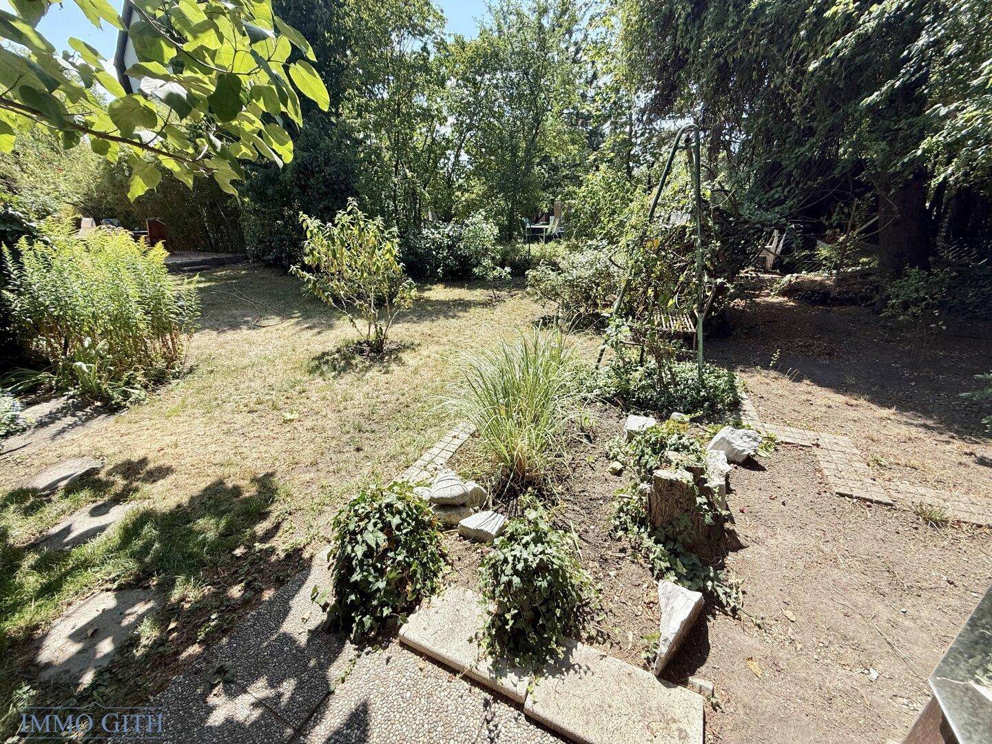 Großer, naturbelassener Garten mit Rasenfläche und verschiedenen Pflanzen, ideal zur Entspannung im Freien.