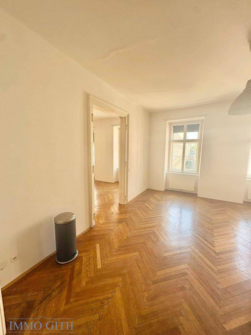Offener Wohnbereich mit Küchenzeile und Fischgrätparkettboden.