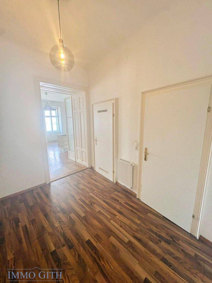 Heller Flur mit Holzboden und Zugang zu weiteren Räumen.
