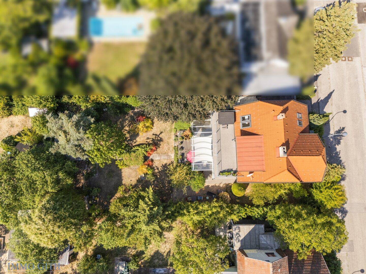 Blick von oben auf den Gartenbereich mit Terrasse und viel Grünfläche hinter dem Haus.
