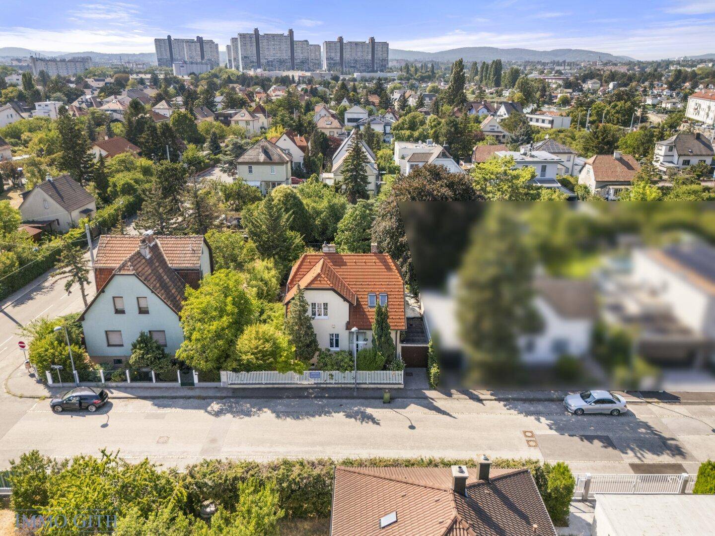 Weitläufige Luftaufnahme des Hauses in einer grünen Wohngegend mit Blick auf die Stadt.