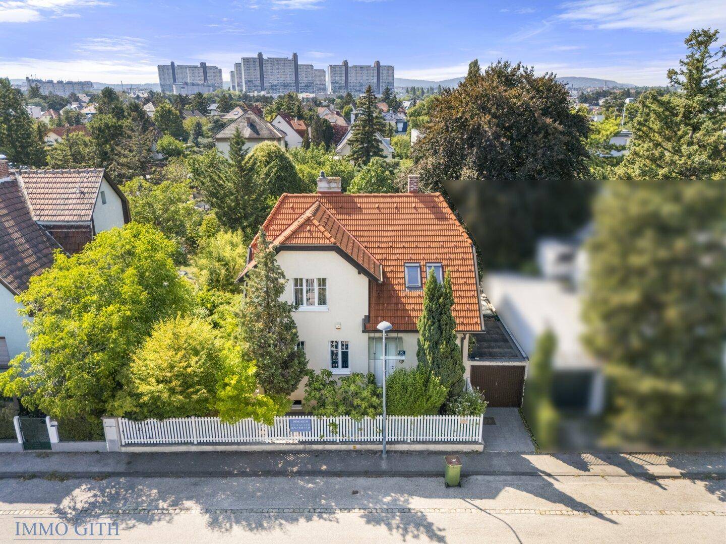 Nahaufnahme des Hauses von vorne mit weißer Fassade, rotem Ziegeldach und gepflegtem Vorgarten.