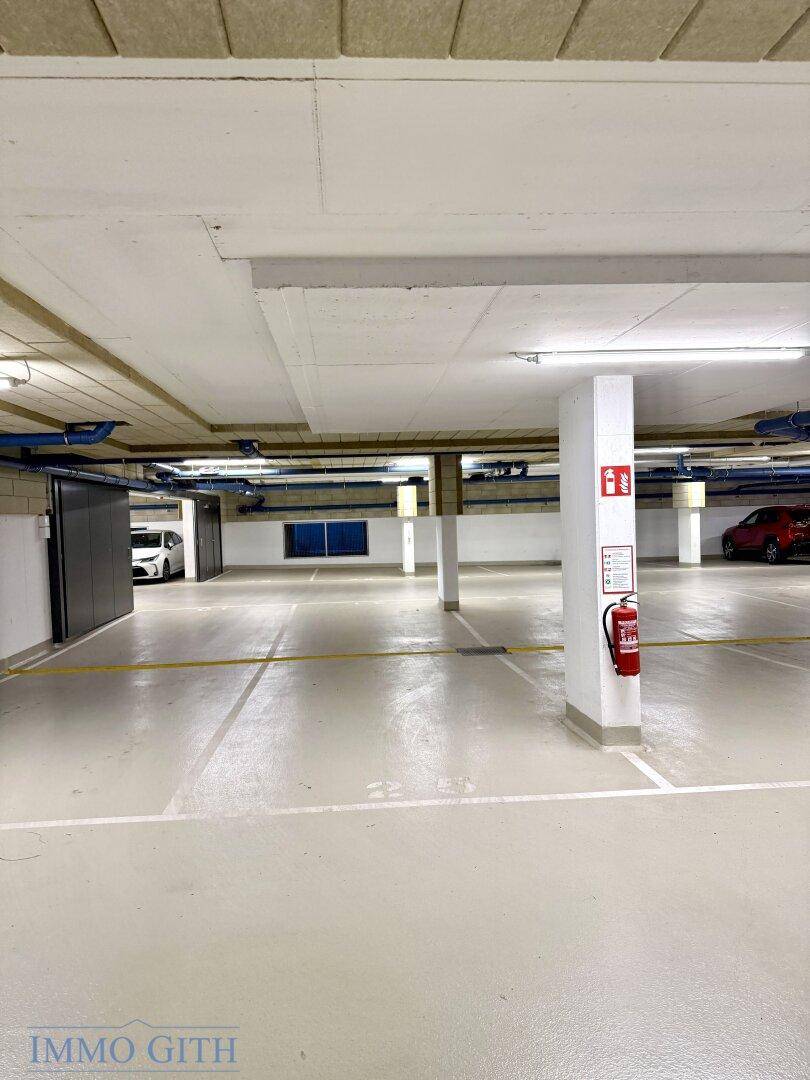 Tiefgarage mit zahlreichen Parkplätzen und praktischen, dunklen Abstellräumen entlang der Wand.
