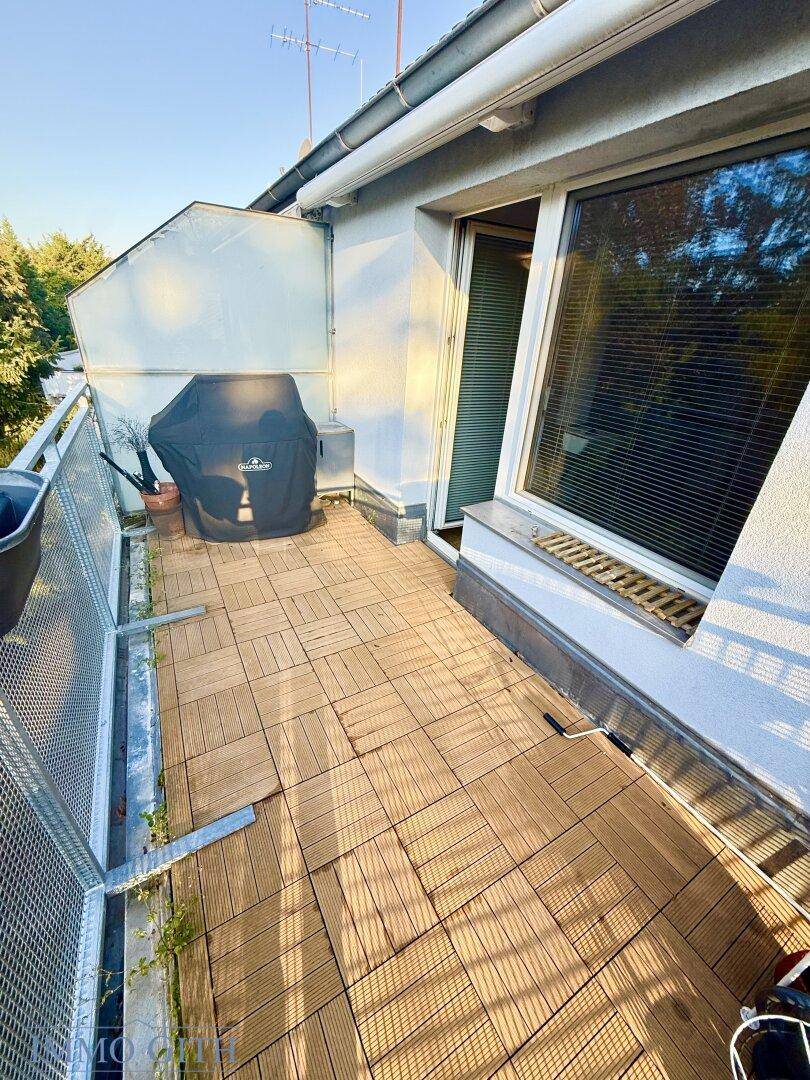 Geräumiger Balkon mit Holzdielenboden und Grill, ideal für entspannte Stunden im Freien.