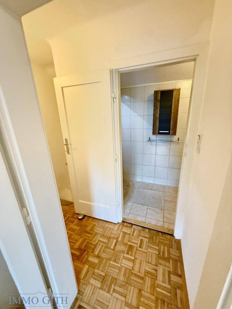 Heller Flur mit Parkettboden, der zu einem Badezimmer führt.