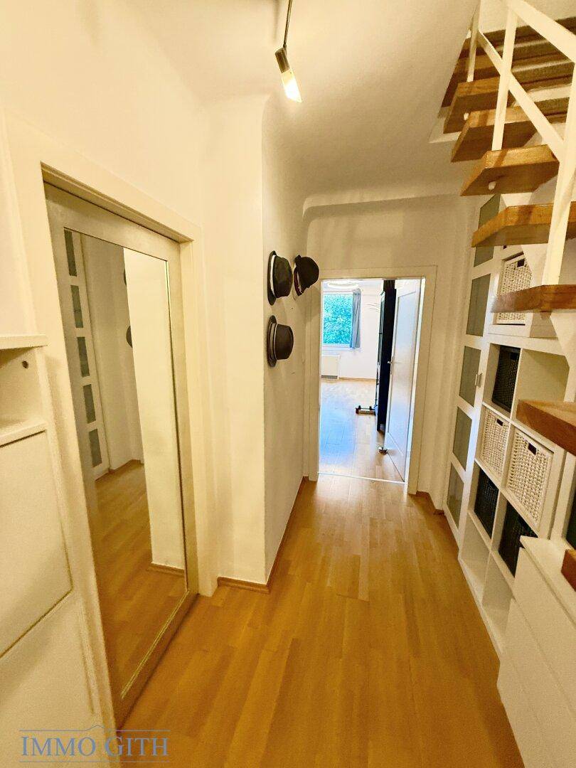 Langer Flur mit Parkettboden und Spiegeltür, der zu weiteren Zimmern führt.