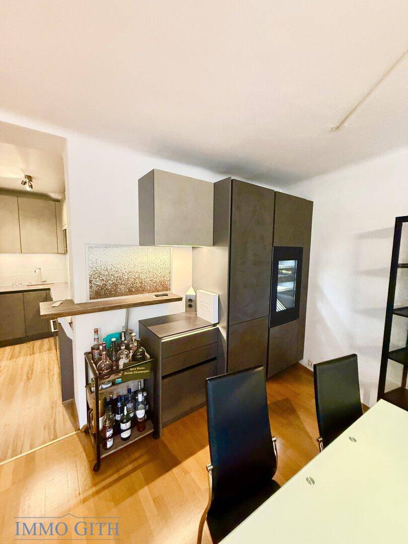 Moderner Küchenbereich mit integriertem Weinkühlschrank und Bartheke, offen zum Essbereich.