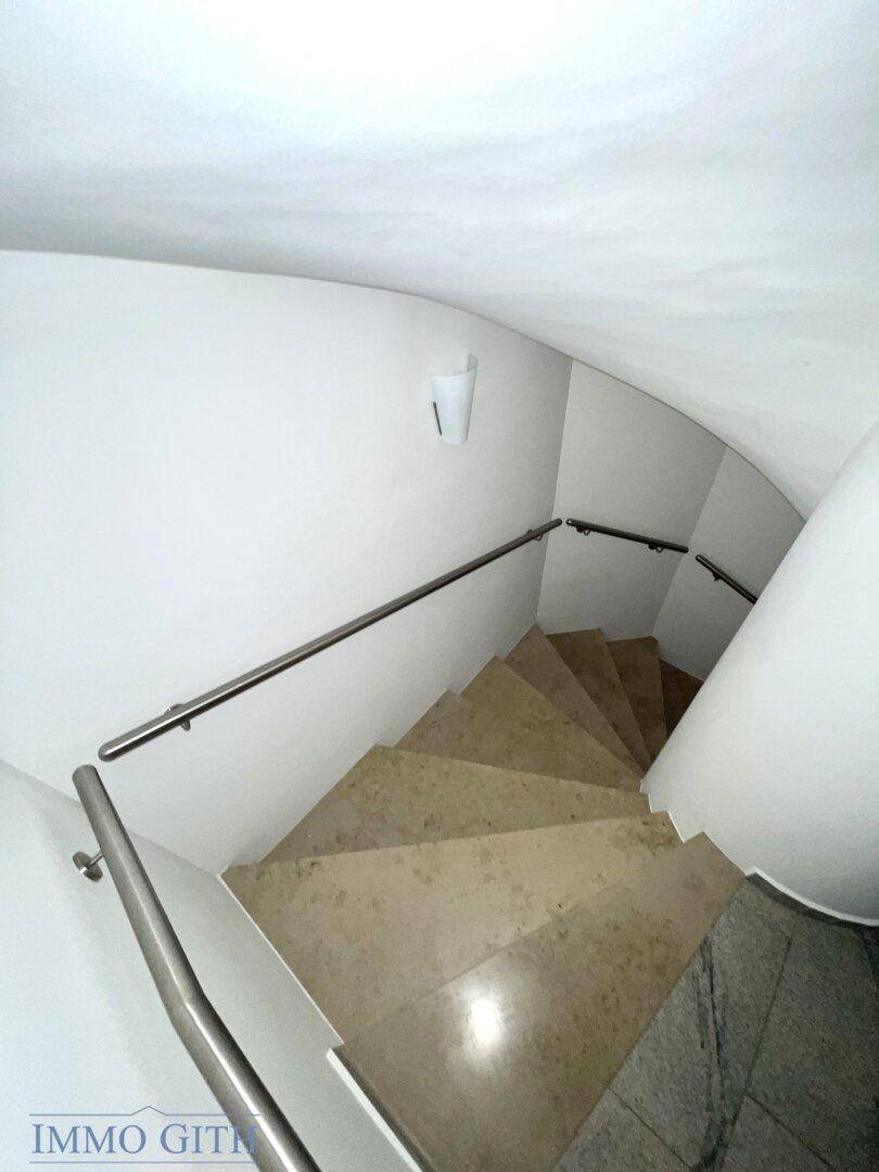 Elegante Wendeltreppe mit Metallgeländer und Steinbelag, die die verschiedenen Etagen verbindet.