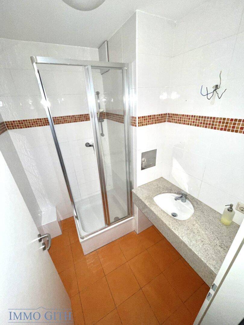 Badezimmer mit Duschkabine, Granit-Waschtisch und Terrakotta-Fliesen, in gutem Zustand.