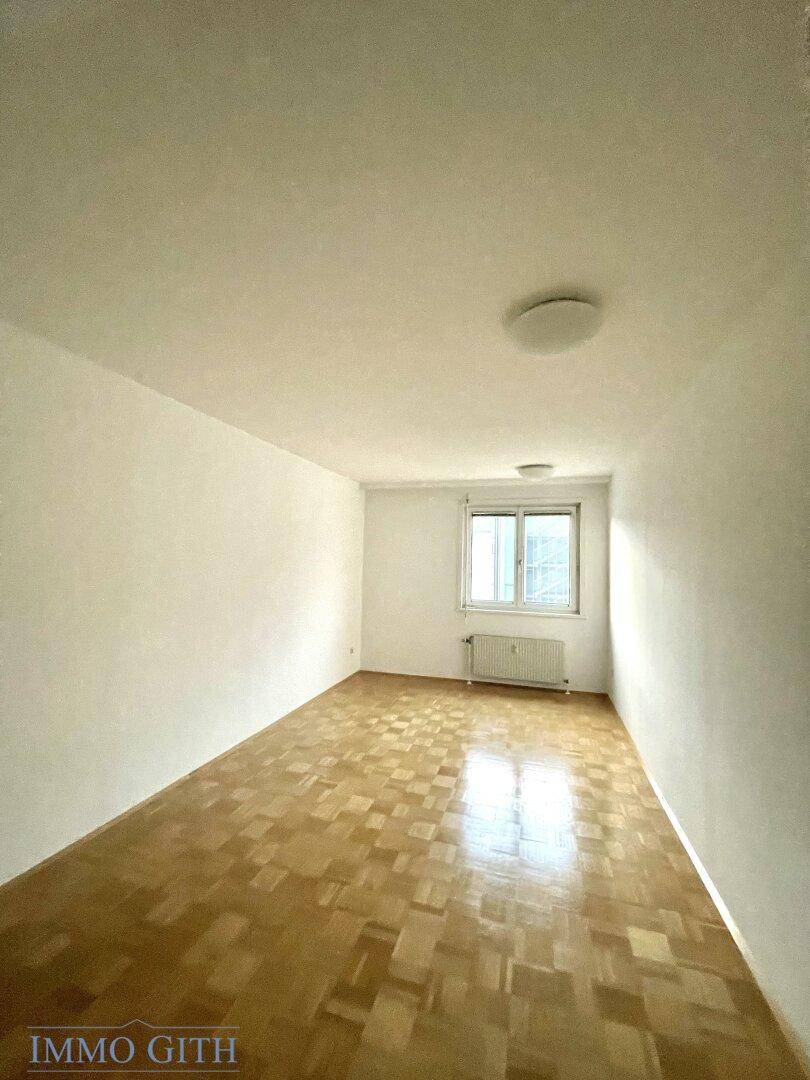 Ruhiges Schlafzimmer mit Parkettboden und einem Fenster, das für natürliche Belichtung sorgt.