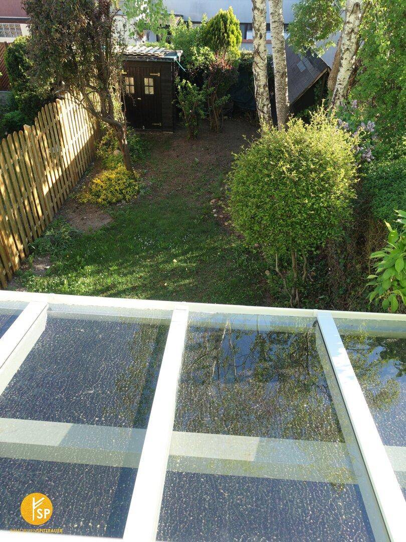 Blick von oben auf einen gepflegten Garten mit Rasenfläche und Gartenhaus.