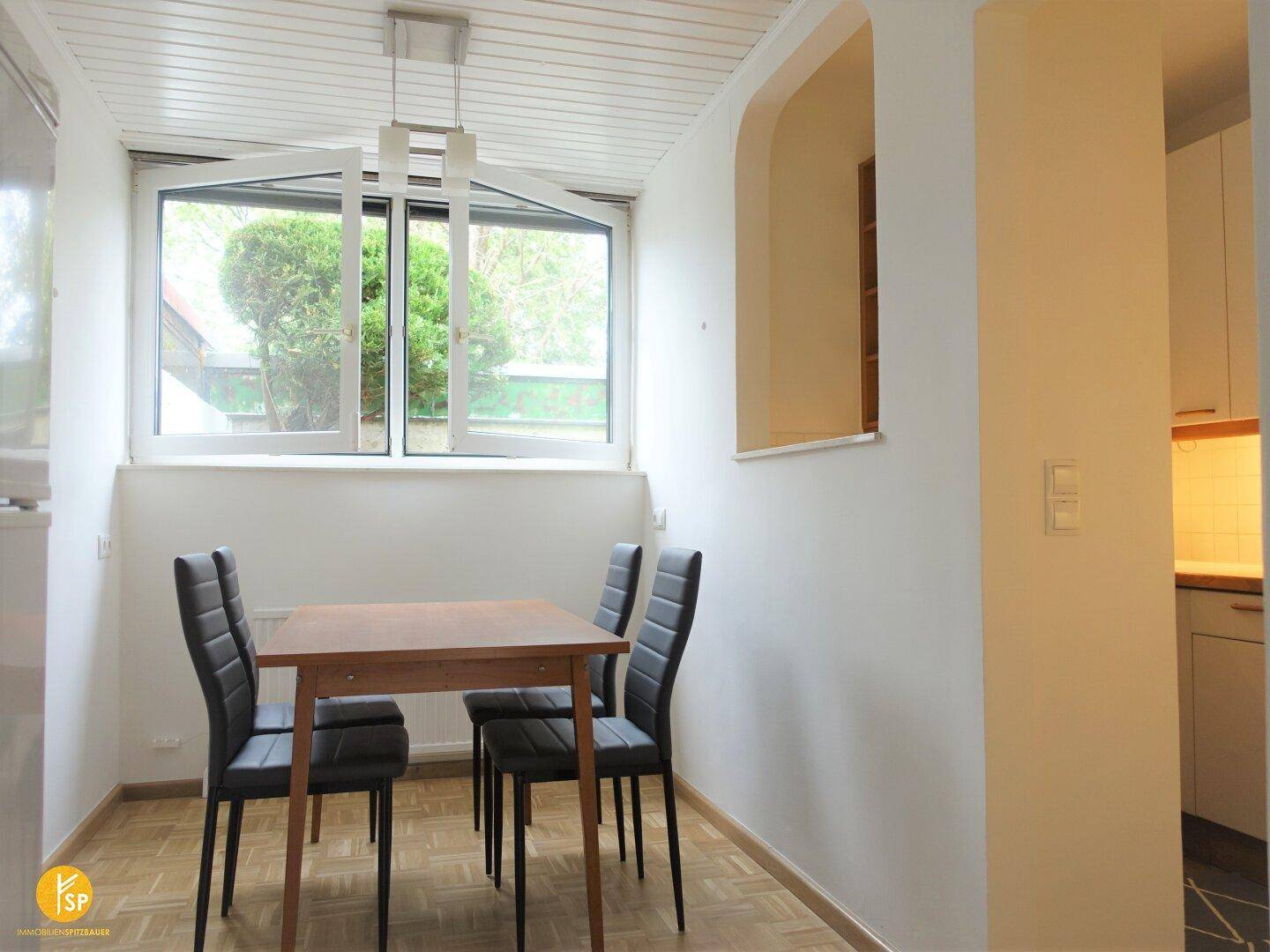 Gemütlicher Essbereich mit Holztisch und Stühlen, direkt am Fenster mit Blick ins Grüne.