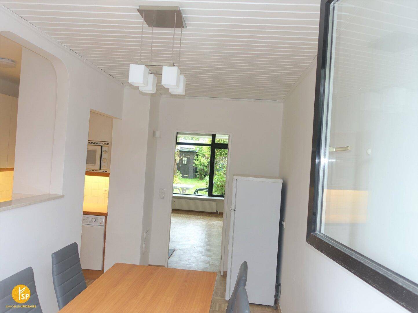 Essbereich mit Zugang zum Wohnzimmer und Blick in den Garten, inklusive Kühlschrank.
