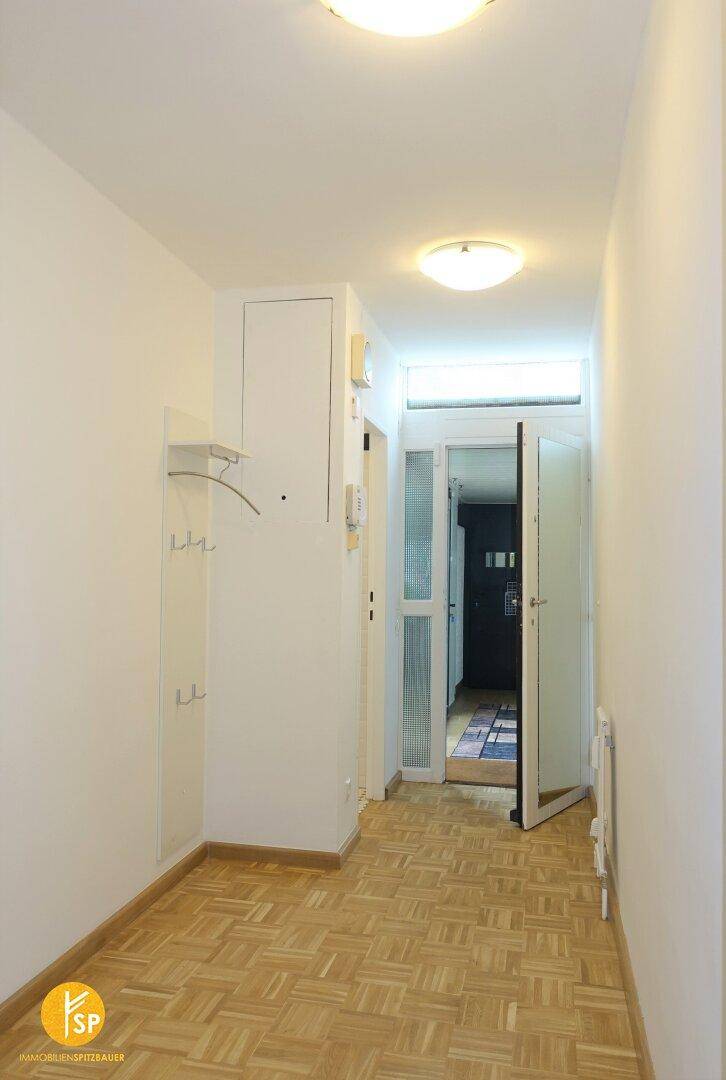 Heller Eingangsbereich mit Holzparkettboden, Garderobe und Zugang zu weiteren Räumen.